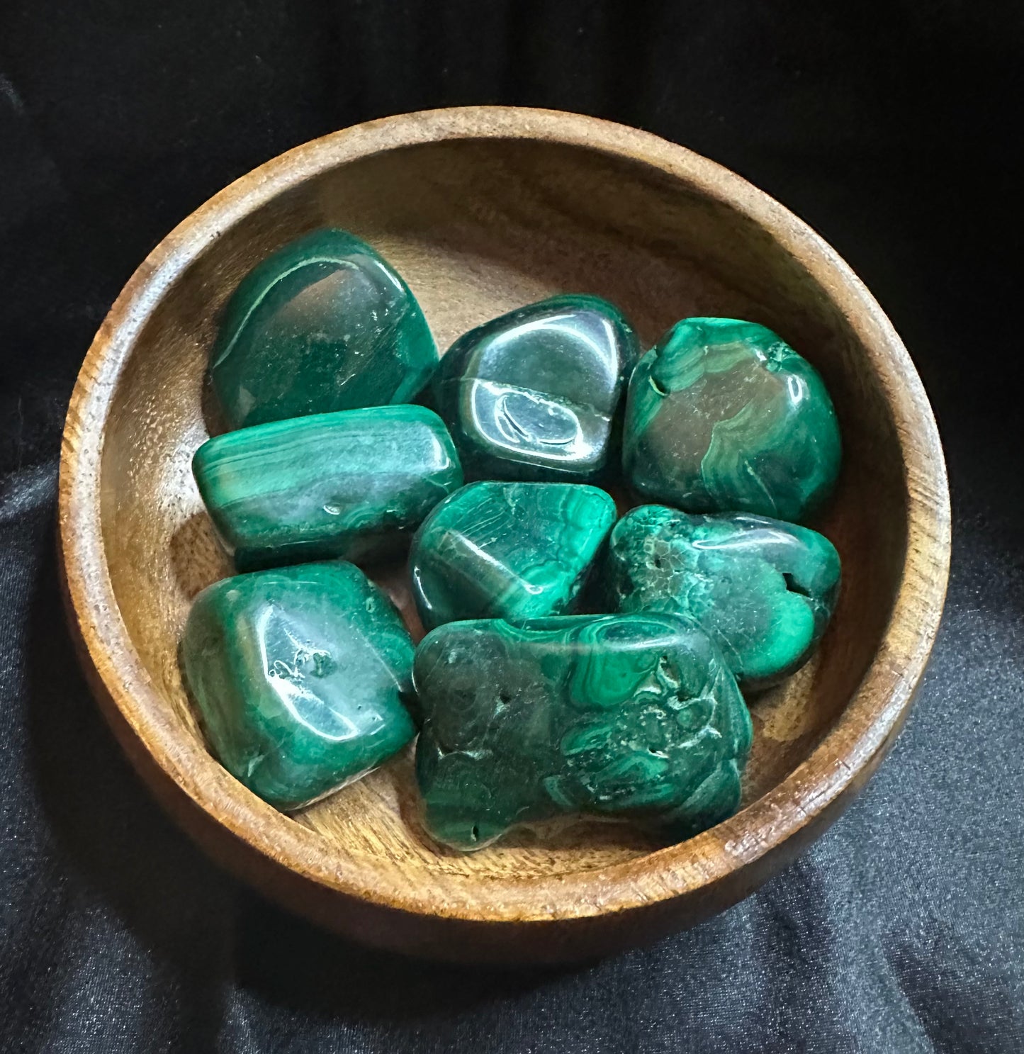 Malachite tumbled stone, shown against a dark backdrop