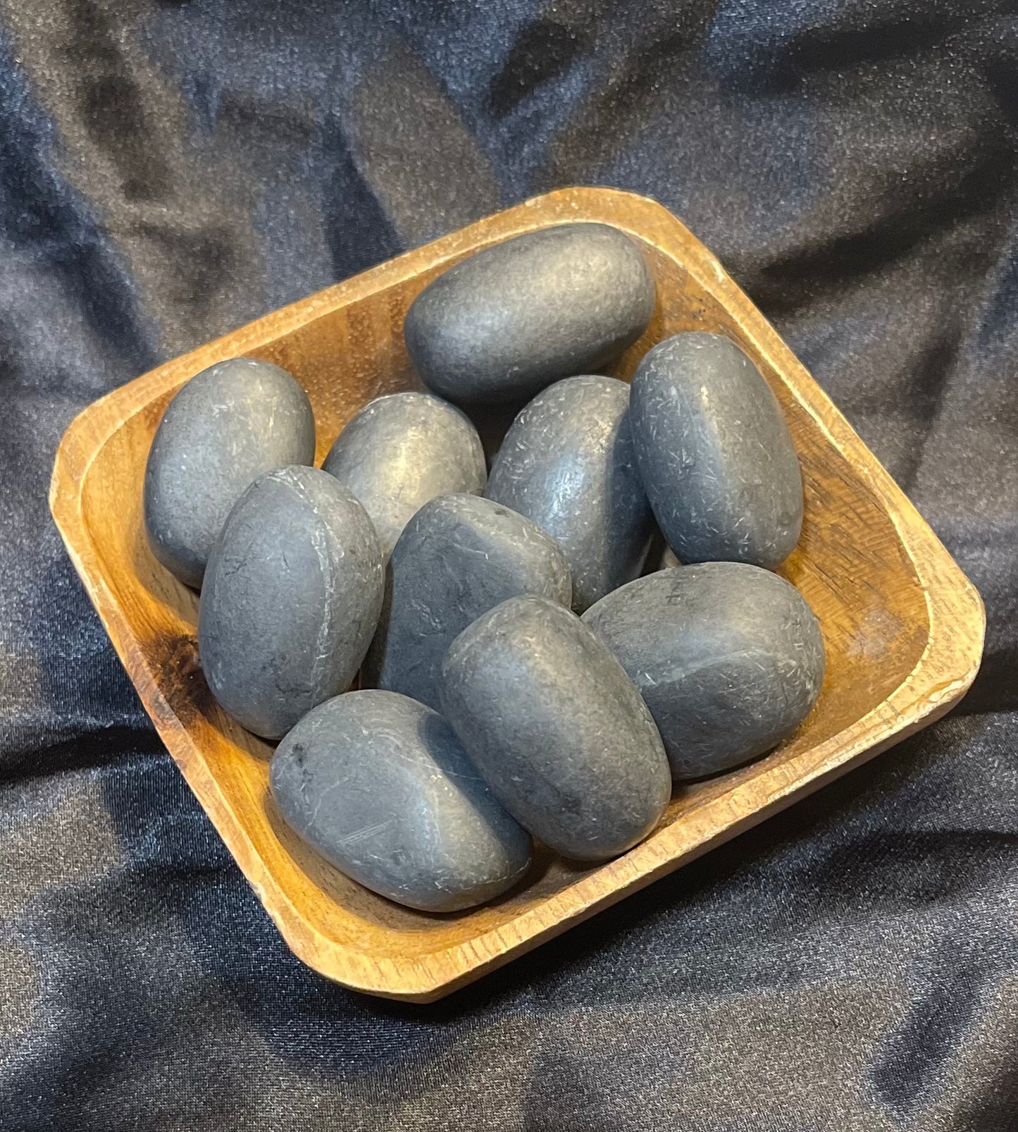 Shungite tumbled stone, held in hand for scale