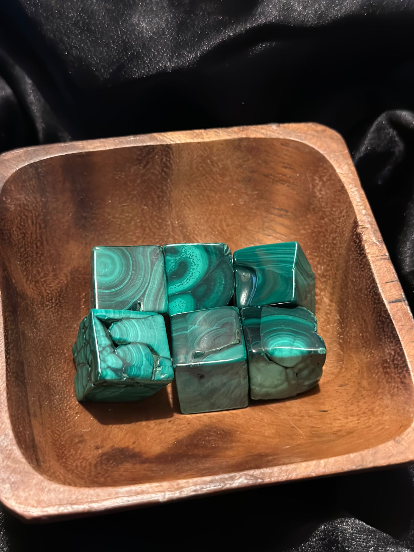 Malachite tumbled stone, held in hand for scale