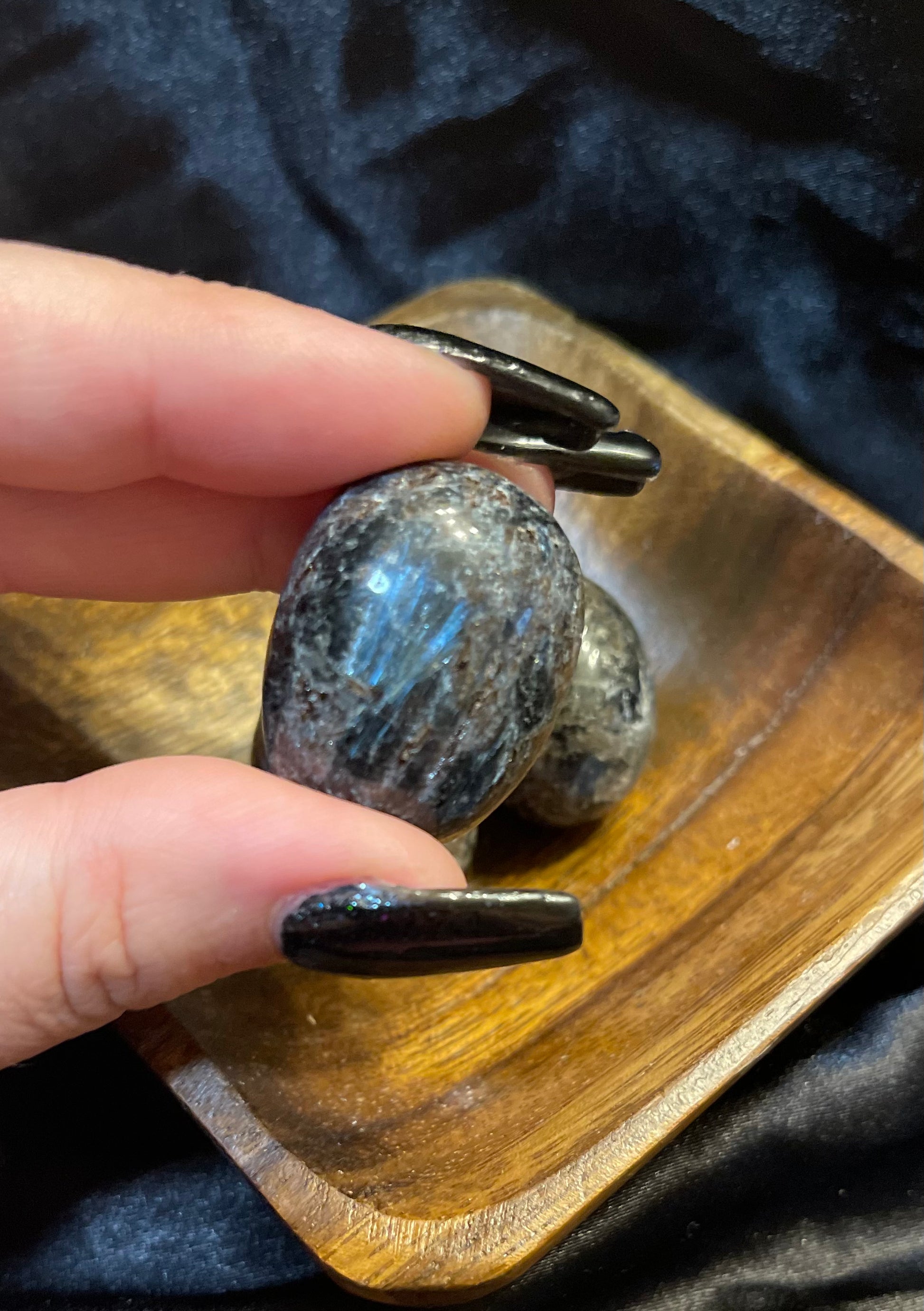 Arfvedsonite tumbled stone, held in hand for scale