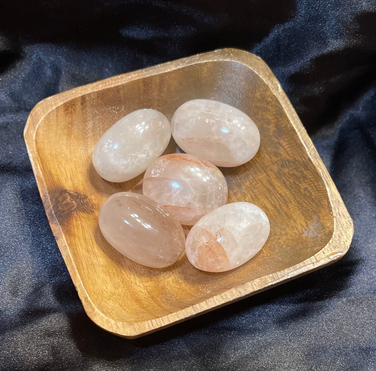 Fire Quartz tumbled stone, held in hand for scale